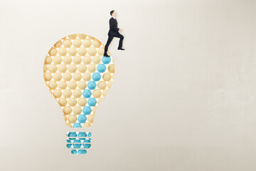 Poster - European man in suit standing on abstract pattern light bulb on light background with mock up place. Idea, growth and success concept.