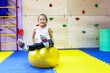 an autistic girl is being treated in a children's center by a psychologist doctor, holding a yellow spiked big ball