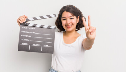 Wall Mural - pretty hispanic girl smiling and looking friendly, showing number two. cinema concept