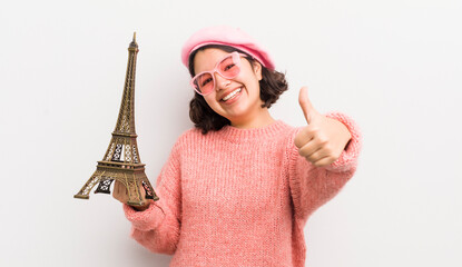 pretty hispanic girl feeling proud,smiling positively with thumbs up. paris concept