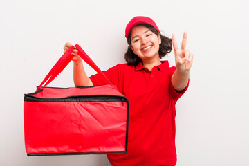 Wall Mural - pretty hispanic girl smiling and looking happy, gesturing victory or peace. fast food delivery concept