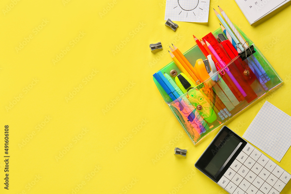 Pencil case with different stationery and calculator on yellow background