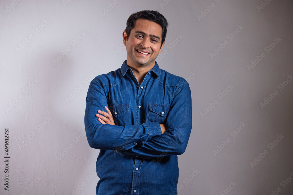 Portrait of young man in blue shirt standing with hands crossed Stock ...