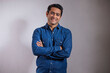 © IndiaPix - Portrait of young man in blue shirt standing with hands crossed
