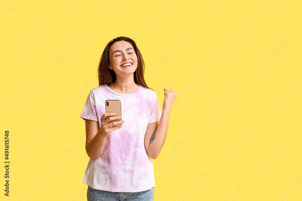 Happy woman checking mobile phone on yellow background. E-mail concept