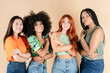 © PintoArt - Female models with different skins standing together and smiling. Group of happy young women on brown background.