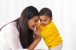 © IndiaPix - Little baby with toy in hand standing with the help of mother