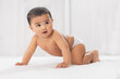 © IndiaPix - Cute baby in diaper crawling on bed
