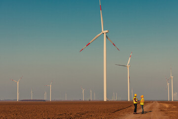 Engineers looking and checking wind turbines at field