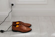 Shoes with electric dryer on floor indoors, space for text
