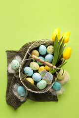 Poster - Basket with painted Easter eggs and tulip flowers on green background