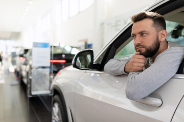 Wall Mural - Buyer Sitting in a new car at a car dealership thinks about buying a car on credit