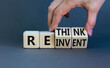 Reinvent and rethink symbol. Businessman turns cubes and changes the concept word Reinvent to Rethink . Beautiful grey table grey background. Business reinvent and rethink concept. Copy space.