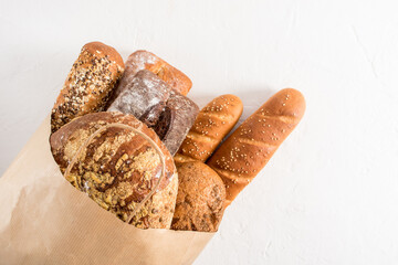 Wall Mural - Kraft bag filled with various types of bread from the bakery. Zero waste, eco shopping and delivery. white background.