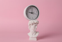 Antique David Bust With Clock On Pink Background. Conceptual Pop. Minimal Still Life. Creative Idea