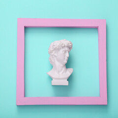 Wall Mural - David bust in pink frame on blue background. Creative layout. Minimal still life. Flat lay. Top view