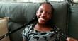 © Marco - Teen black African girl smiling at camera sitting at couch