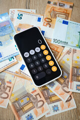 iPhone is open in the calculator application and lies on the money. Cash in euros for payment or exchange. A man calculates his salary in euro banknotes