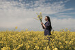 © Milou Dirks - Woman in classic blue dress standing in field of yellow musterd seed flowers in spring