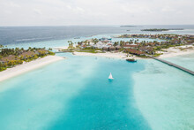Aerial View Of Sailboat Sailing In Clear Blue Ocean Bay Near Luxury Resort In Male, Maldives.