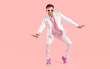 Happy millennial guy in suit and pink converse dance on pink studio background. Smiling stylish young Caucasian man in formalwear and tennis shoes make moves have fun. Fashion and style.