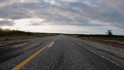 Sticker - Traveling along the countryside route . Point of view of a car driving the asphalt road in the open field at sunset.