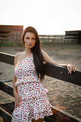 Wall Mural - Girl with long black hair in the countryside. Ipadrome with horses. Rural landscapes, wild west.