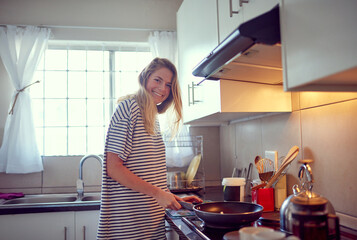 Poster - Preparing one of her classic dishes. Portrait of an attractive young woman cooking in her kitchen.