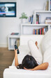 © C S W/peopleimages.com - Shes tuned in. Shot of a young woman watching TV while relaxing on her sofa at home.