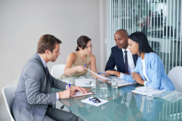 Poster - The business strategists. Shot of a group of businesspeople going over documents during a meeting.