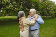 © Studio Romantic - Portrait of happy married senior couple dancing waltz amongst greenery and chestnut trees of beautiful summer park. Two old people in love enjoying each other's company and having good time in nature