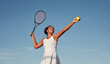 Black sportswoman playing tennis against blue sky