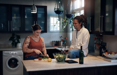 Wall Mural - Preparing a healthy supper. Shot of a young couple bonding in the kitchen while preparing a salad.