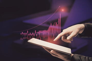 Close up of businessman hand pointing at tablet with abstract glowing growing global business chart on blurry officr desktop background. Financial growth and trade concept. Double exposure.