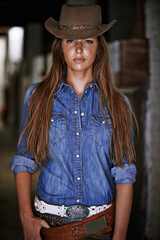 Canvas Print - Being a cowgirl is who she is. An attractive young cowgirl standing in the stables.