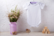 White Baby Short Sleeve Bodysuit Mockup With Wild Flowers And Wooden Children Toys