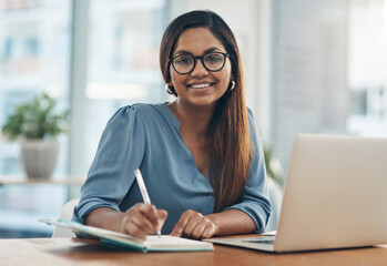 Poster - Diligence always leads to results. Portrait of a young businesswoman writing notes while working in an office.