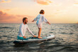 © _KUBE_ - Surfing with sup board. Instructor teaches the pre-school girl to swim with a sup board. Sea and the sunset in the background. Summer vacations