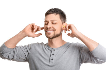 Canvas Print - Handsome man putting yellow ear plugs on white background