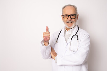 Wall Mural - Senior grey-haired doctor man standing over isolated white background happy face smiling with thumb up looking at the camera. Positive person.