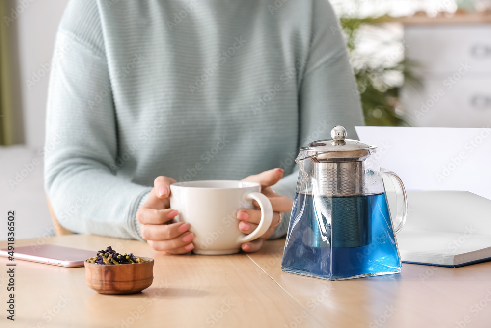 Woman drinking tasty blue tea at table