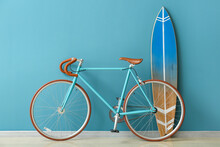 Bicycle And Surfboard Near Color Wall In Room