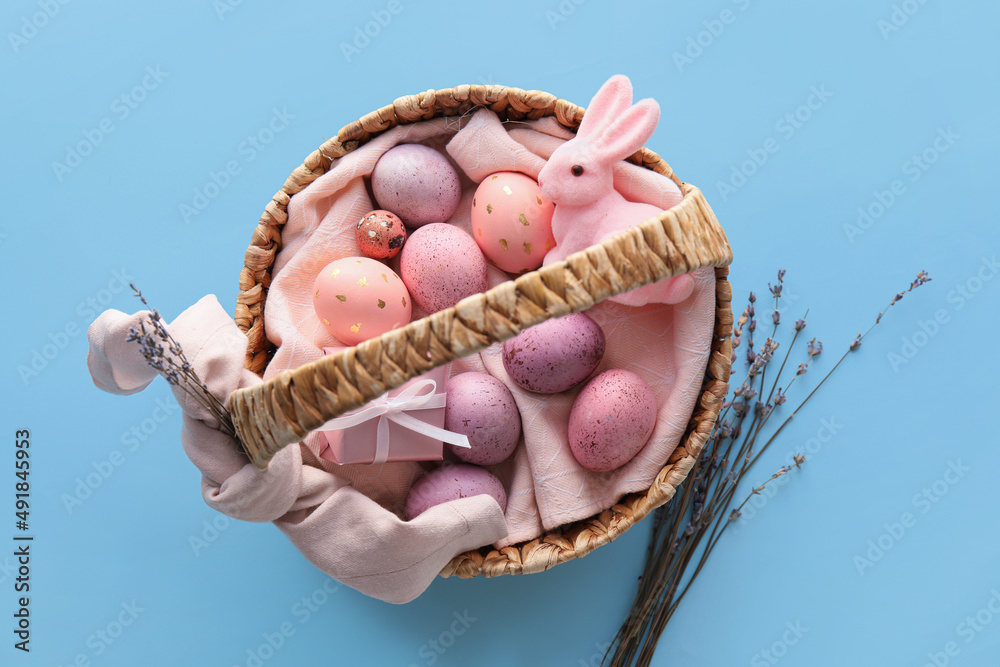 Basket with painted Easter eggs, lavender and bunny on blue background