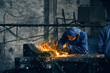 Close up of man in special dark blue uniform making gates from iron in garage or workshop. Concept of process working with grinding machine in garage. 