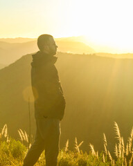 Wall Mural - homem contemplando o nascer do sol com montanhas ao fundo 