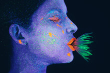 Life In Neon. Shot Of A Young Woman Posing With Neon Paint On Her Face.