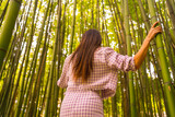 Fototapeta Dziecięca - Young caucasian girl with a pink skirt in a bamboo forest. Enjoying the summer holidays in a tropical climate, strolling back in the forest