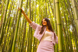 Fototapeta Dziecięca - Young caucasian girl with a pink skirt in a bamboo forest. Enjoying the summer holidays in a tropical climate, walking in the forest grabbing the bamboo trunks