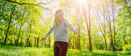 Wall Mural - woman standing in the spring natural park with wide openning hands.