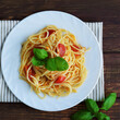 Spaghetti pasta with tomatoes and basil on a wooden table.